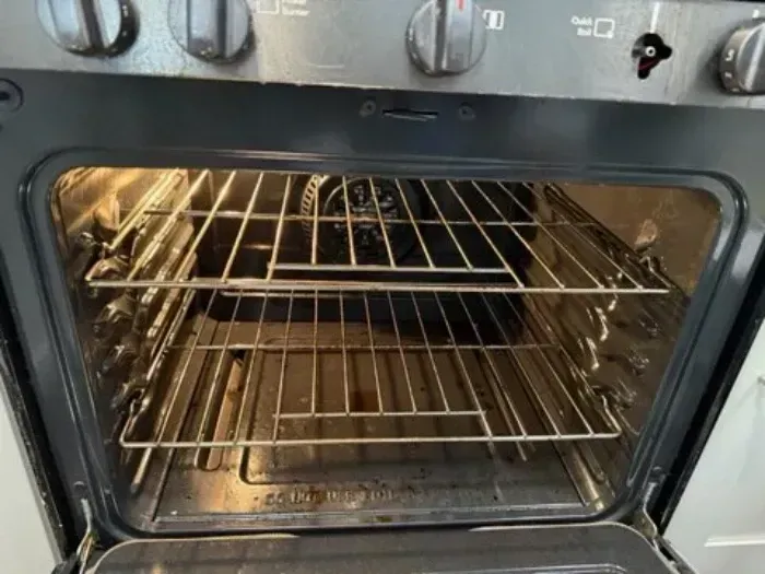 Open oven door with wire racks and a lit interior inside a kitchen appliance