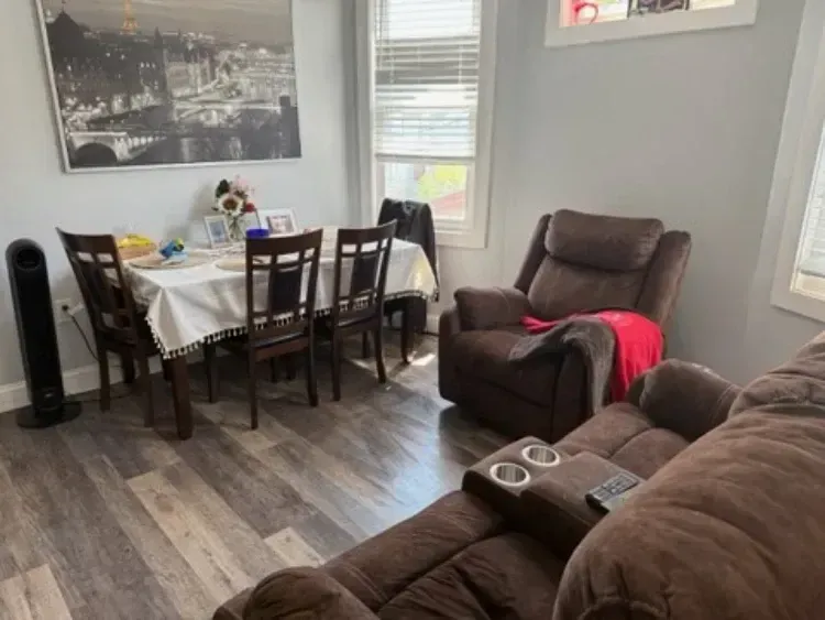 Living room with brown recliners, dining table, gray walls, and cityscape wall art
