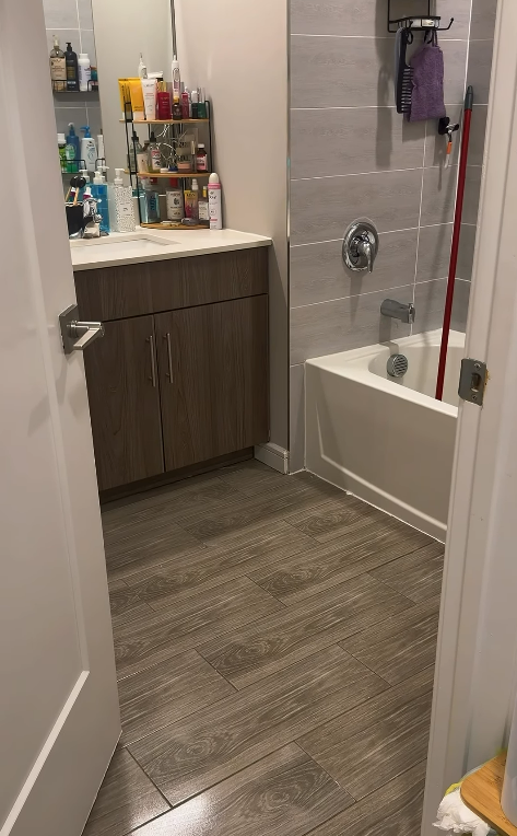 Small bathroom with vanity, tiled floor, and a bathtub/shower with a pink towel.