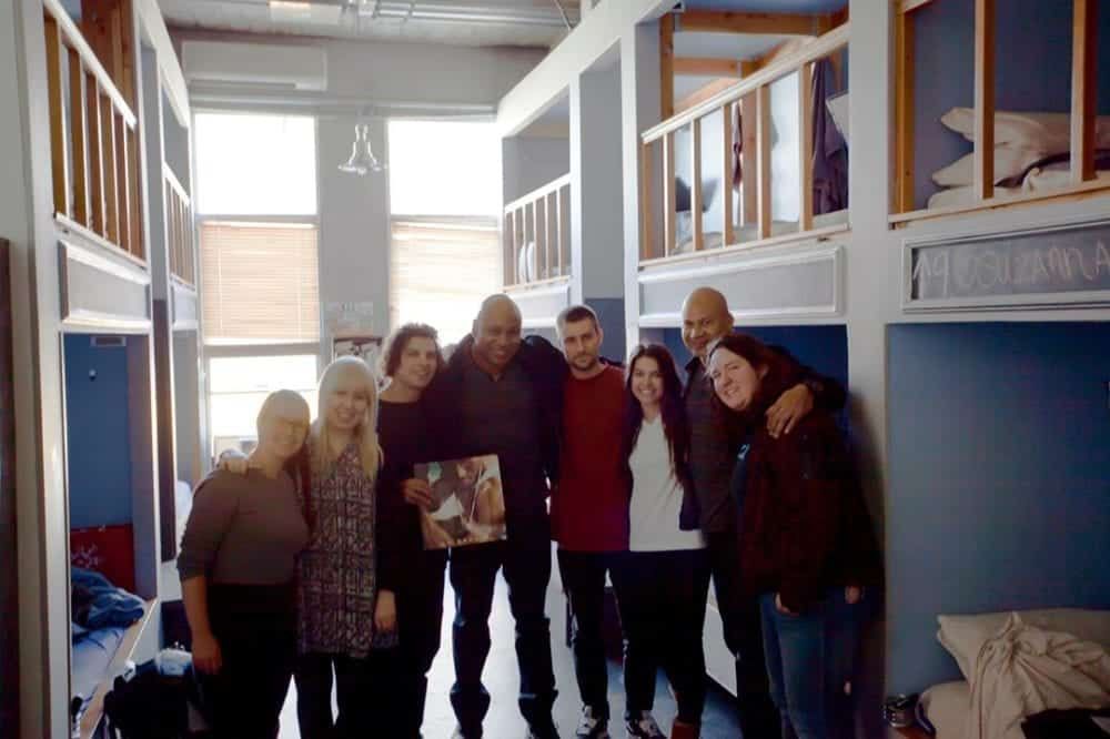 LL Cool J with a group of people smiling, standing in a room with bunk beds.