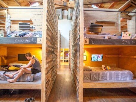 a wide view of a room with bunk beds and a woman sitting on one of the beds