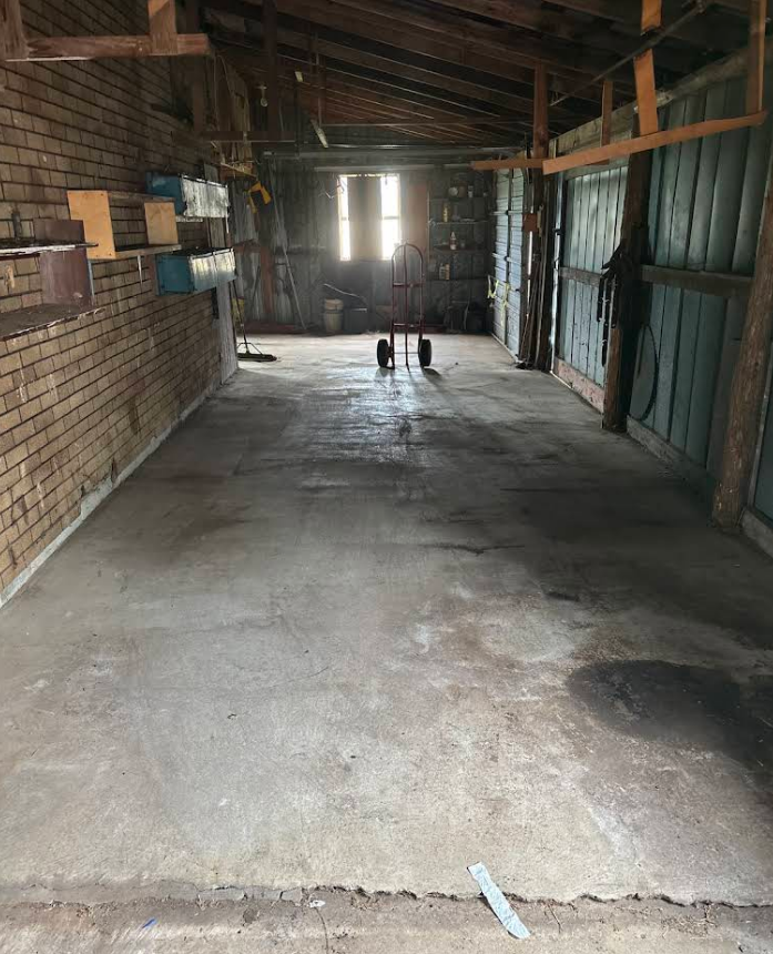 Empty garage with a concrete floor and natural light shining in the back.