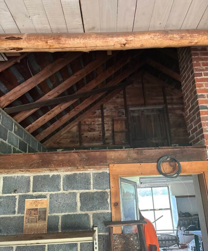 Interior view of an attic space with exposed wooden beams and brick chimney.