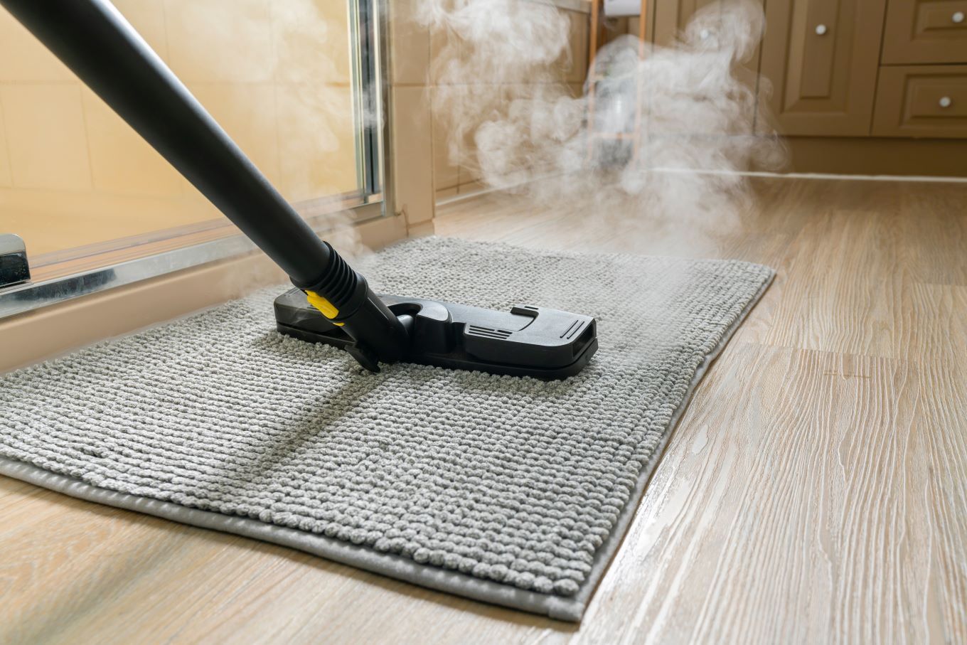 A vacuum cleaner is cleaning a rug on a wooden floor.