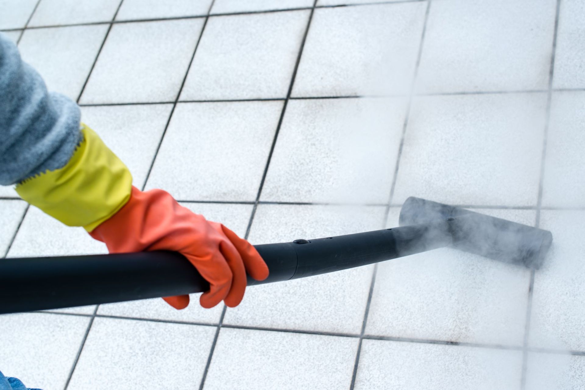 A person is cleaning a tiled floor with a vacuum cleaner.