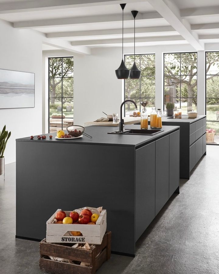Modern kitchen with two dark gray islands, large windows, and fruit crate.