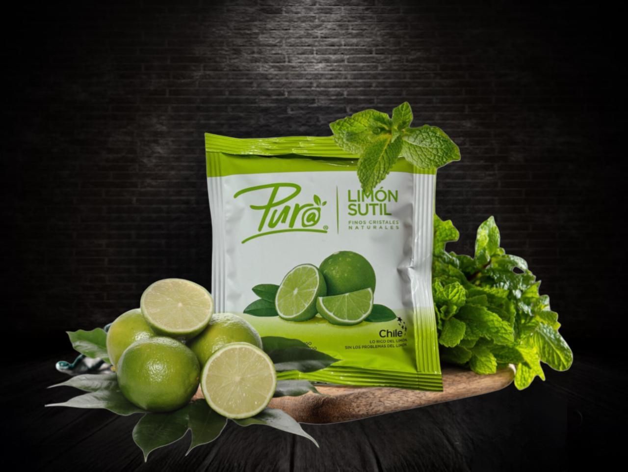 Sobre de mezcla de bebida con sabor a lima rodeado de limas y ramitas de menta sobre una superficie de madera.