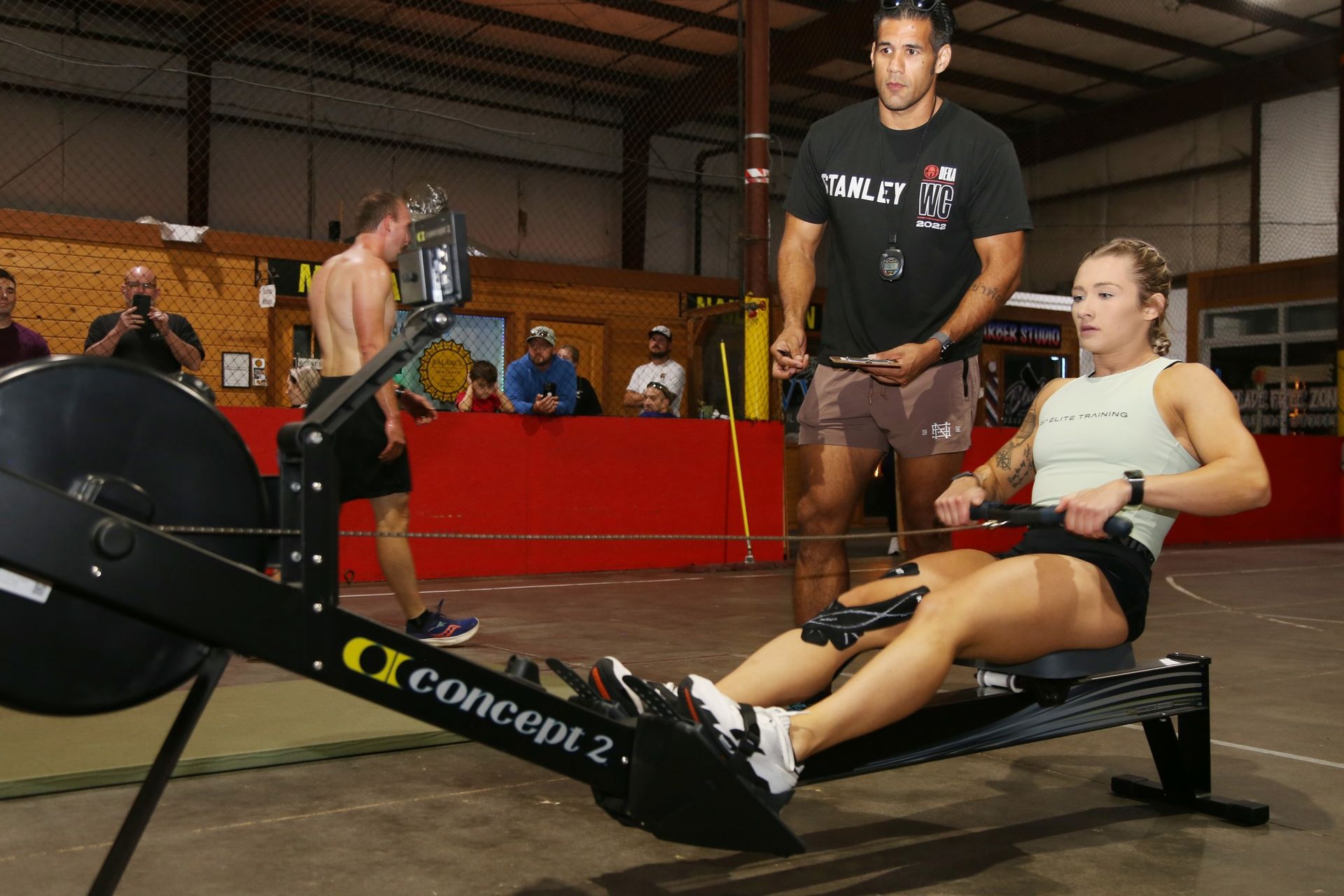 Woman rowing with coach watching in a gym.