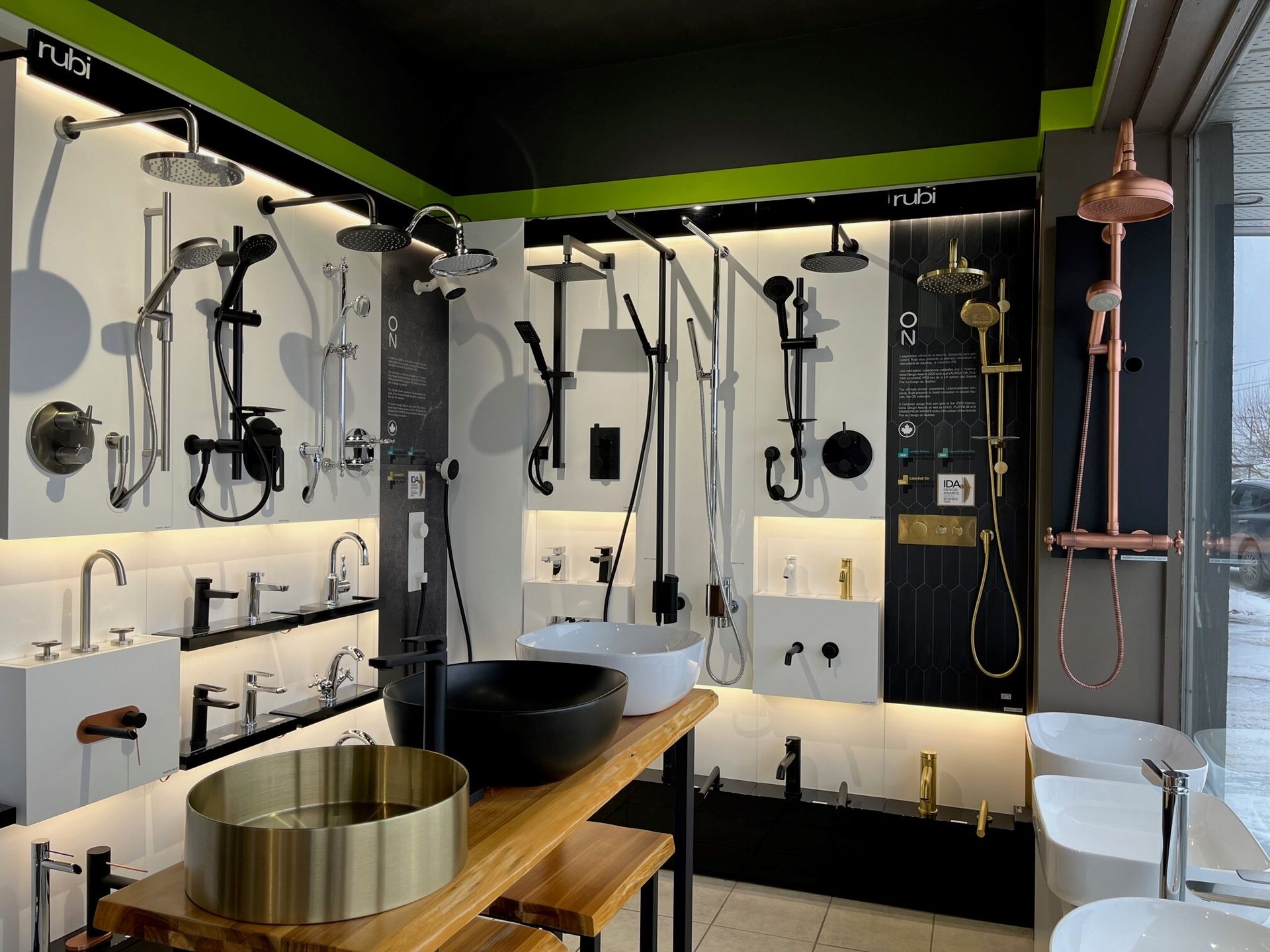 Salle d'exposition de salles de bains modernes avec robinetterie noire et or, meuble-lavabo en bois et baignoire îlot.