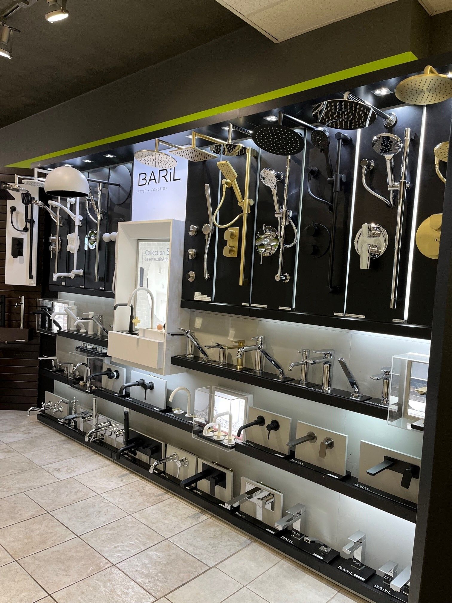 Présentation soignée d'accessoires noirs, argentés et dorés sur des étagères murales dans un magasin carrelé.