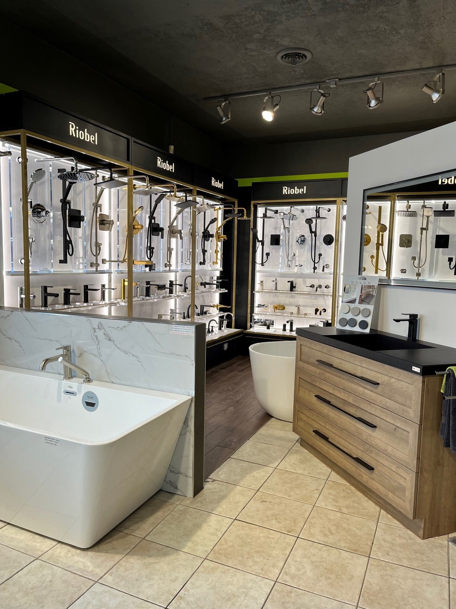 Salle d'exposition de salles de bains modernes avec baignoires îlot, meubles-lavabos et vitrines éclairées.