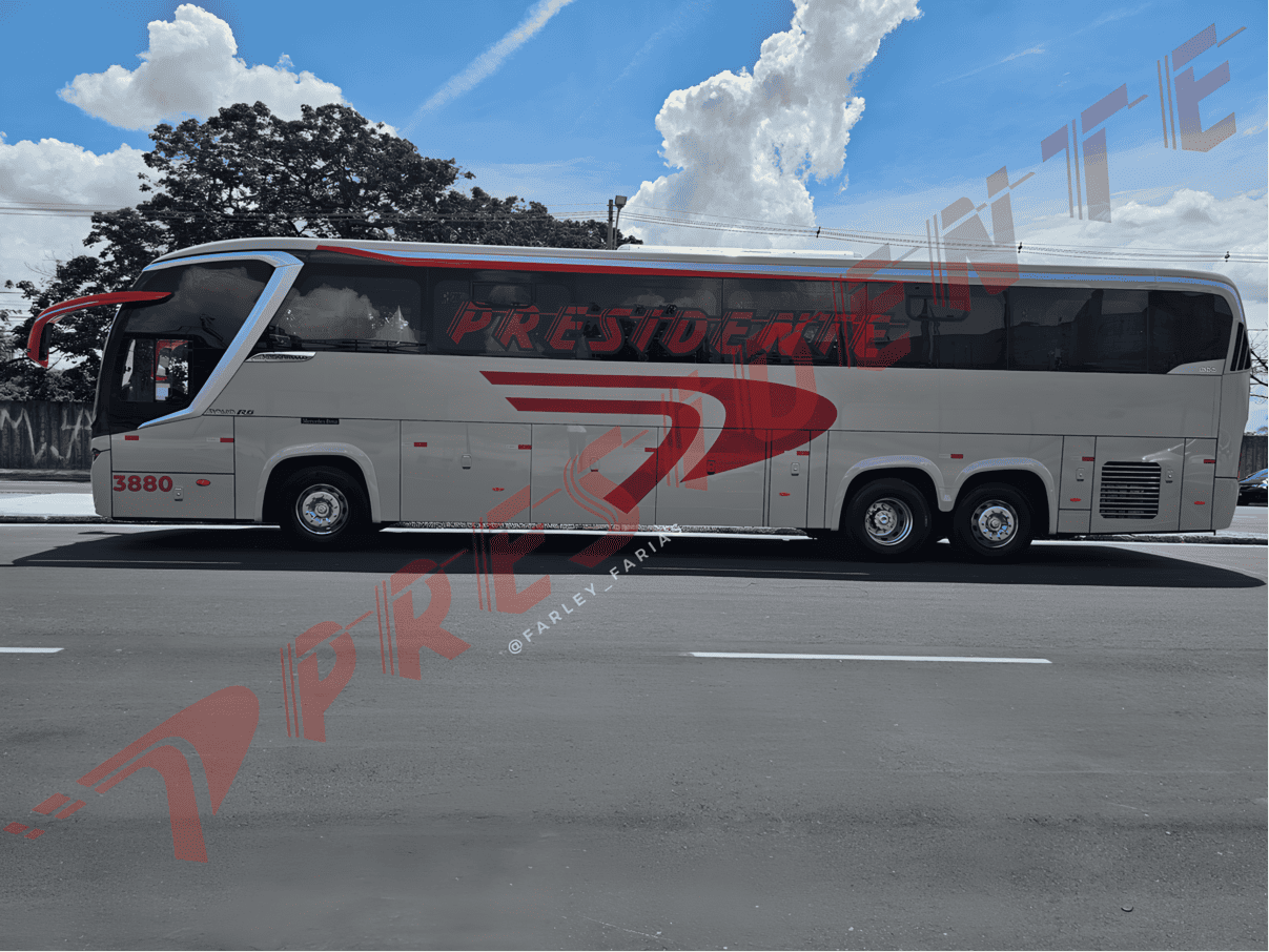 Um grande ônibus de turismo branco e cinza estacionado em uma rua ensolarada sob um céu azul com nuvens.