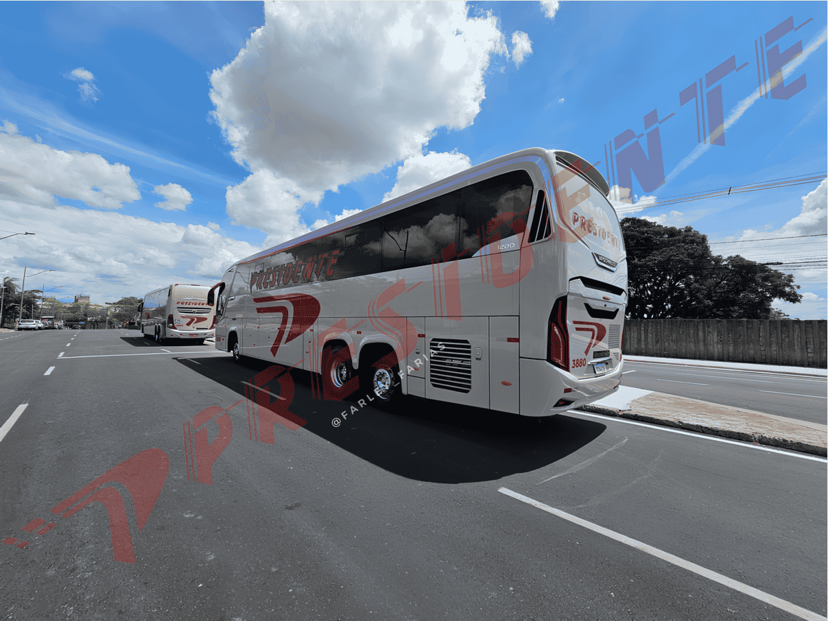 Ônibus de turismo branco trafegando em uma rodovia sob um céu azul parcialmente nublado.