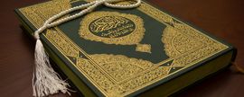 A green and gold book with a tassel is sitting on a table.