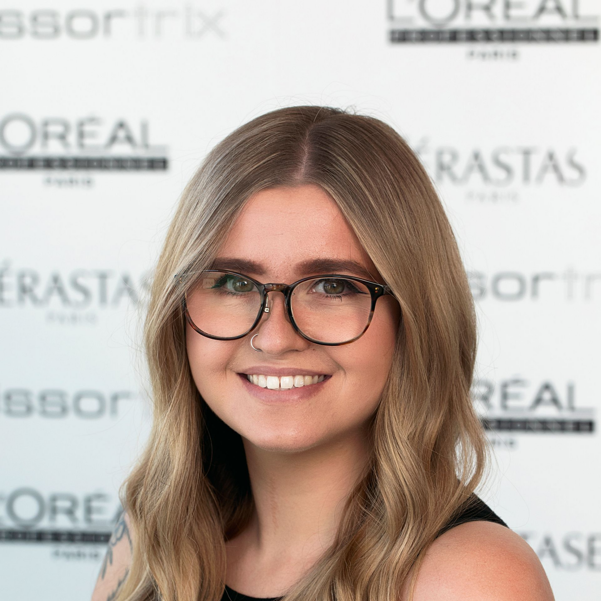 A woman wearing glasses and a black shirt is smiling for the camera.