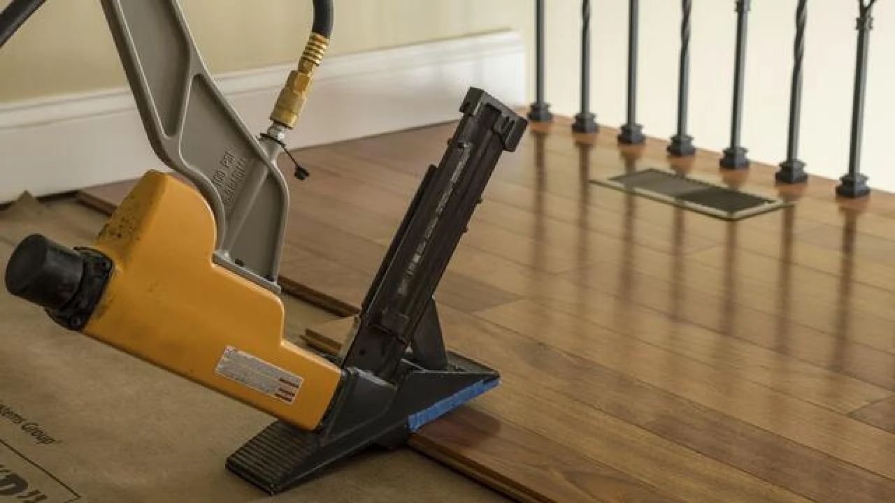 Yellow floor polisher on a hardwood floor near a staircase and railing
