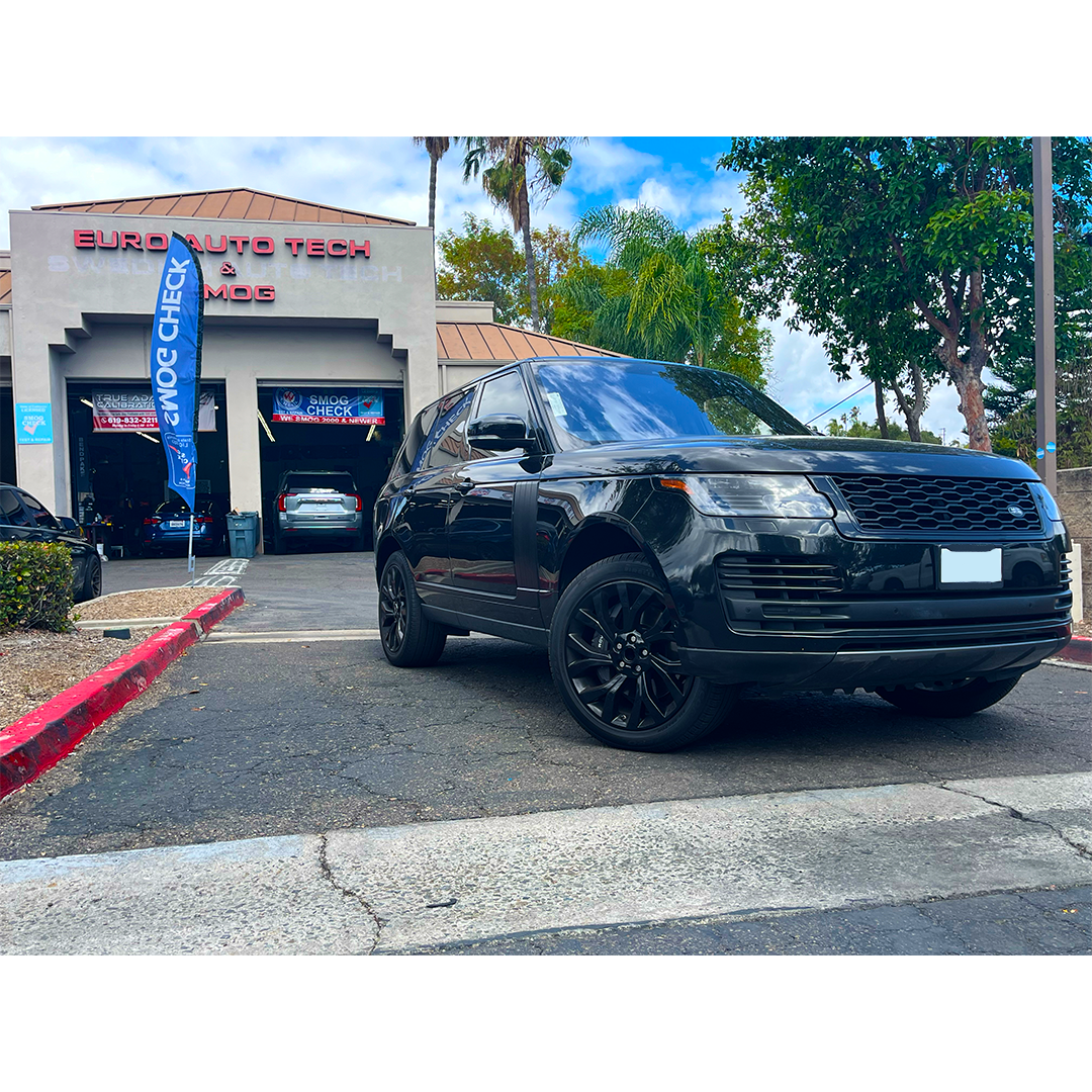 Black SUV parked outside an auto repair shop with blue signage on a sunny day