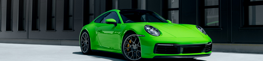 Bright green sports car parked on a paved street in front of modern buildings