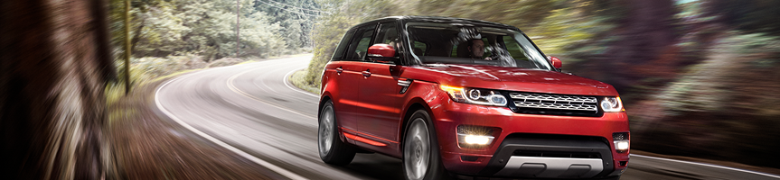 Red SUV driving on a winding road through a blurred forest.