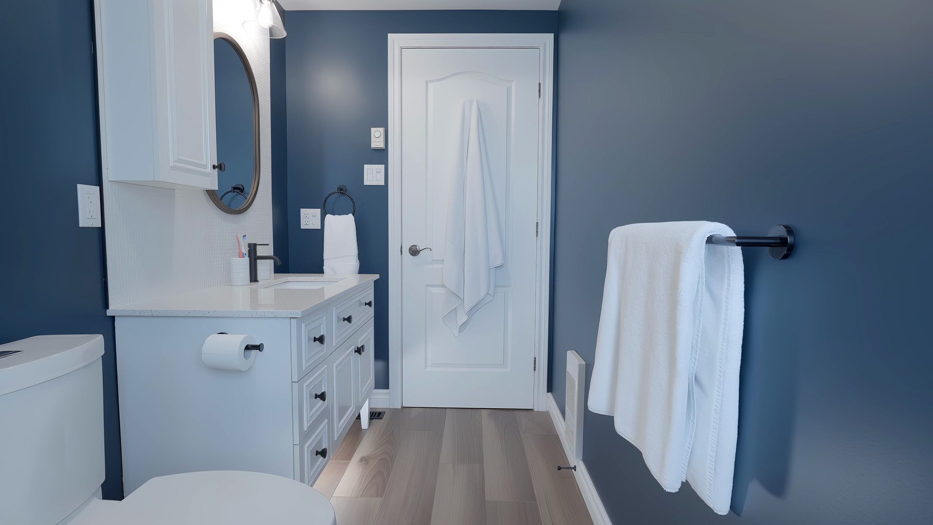 A bathroom with a toilet , sink , mirror and blue walls.