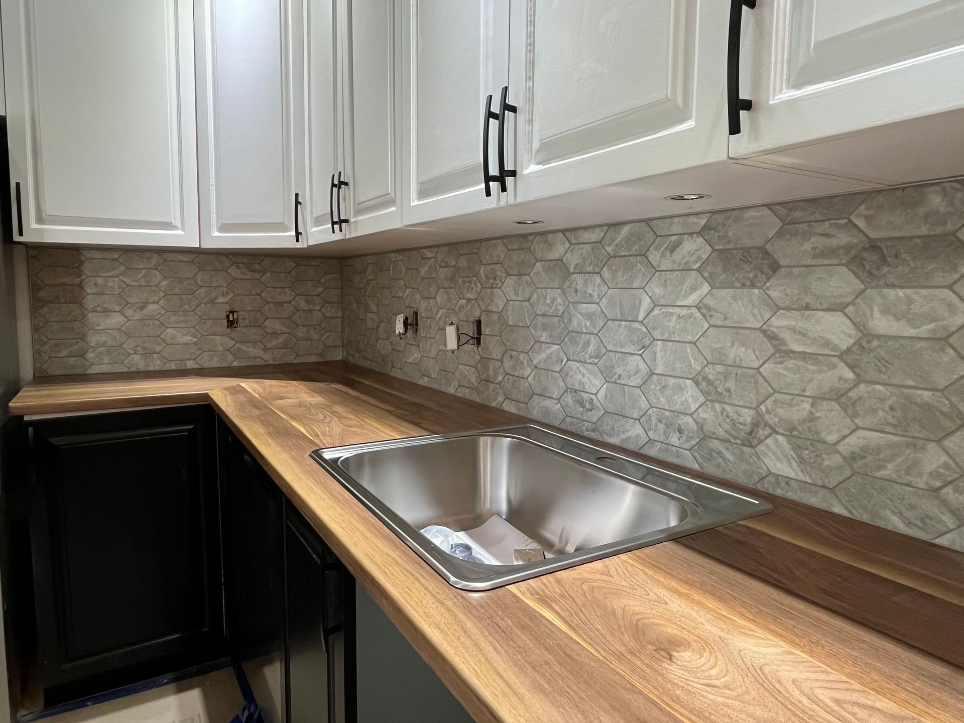 A kitchen with a stainless steel sink and wooden counter tops.