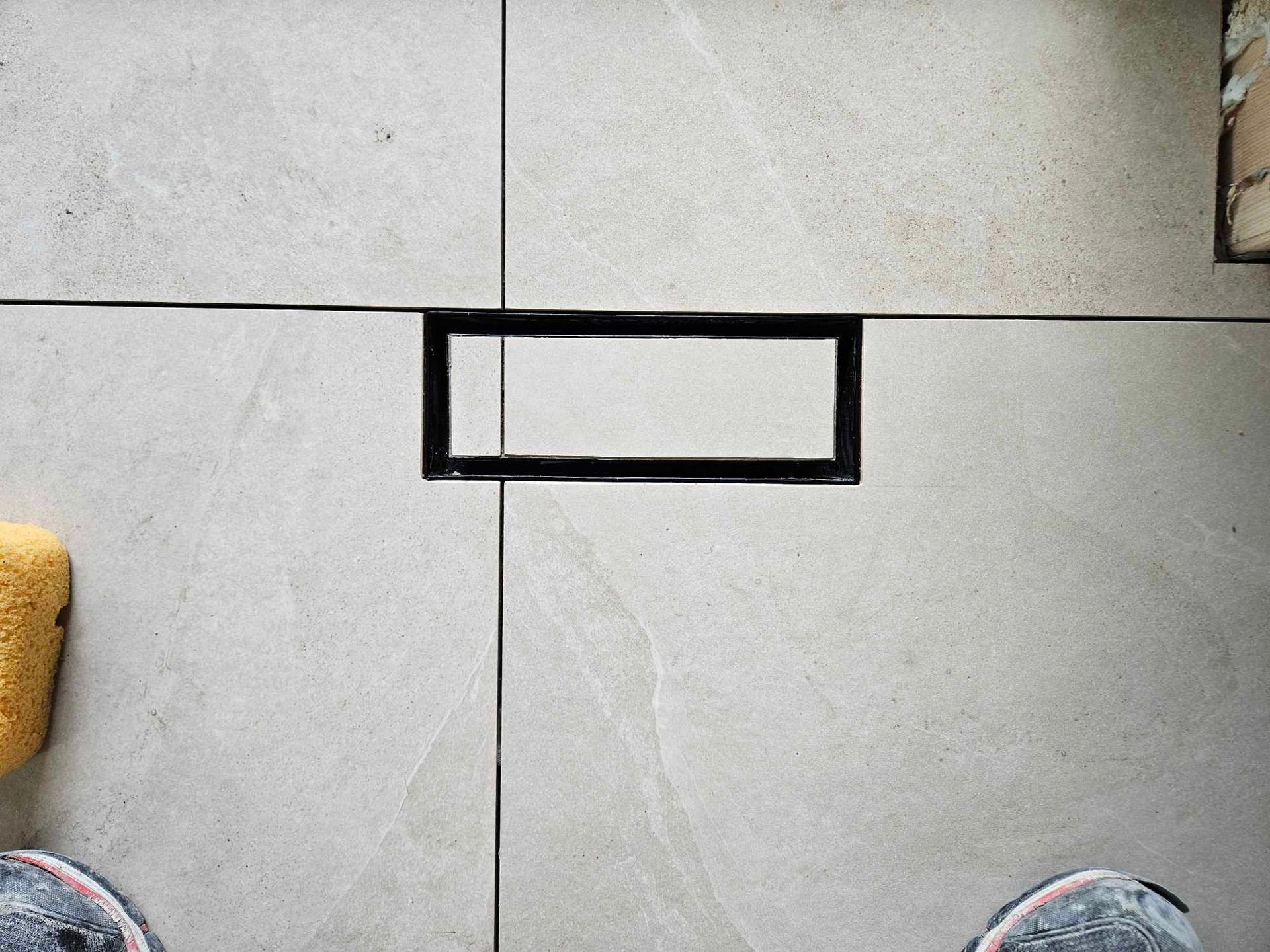 A person is standing on a tiled floor next to a sponge.