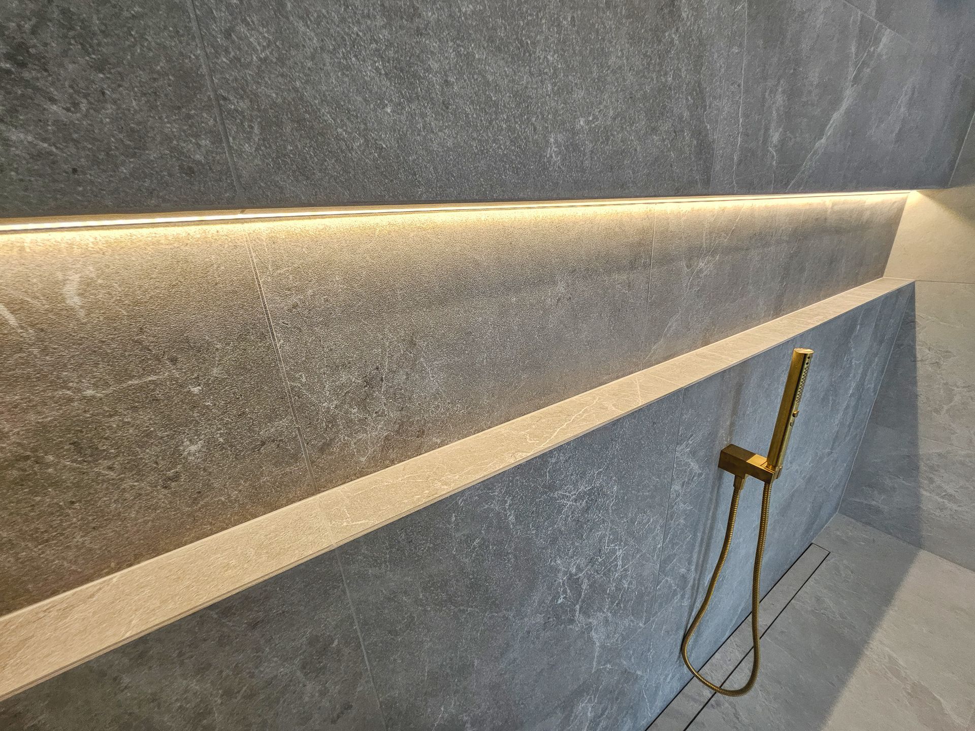A bathroom with a shower head and a light on the wall.