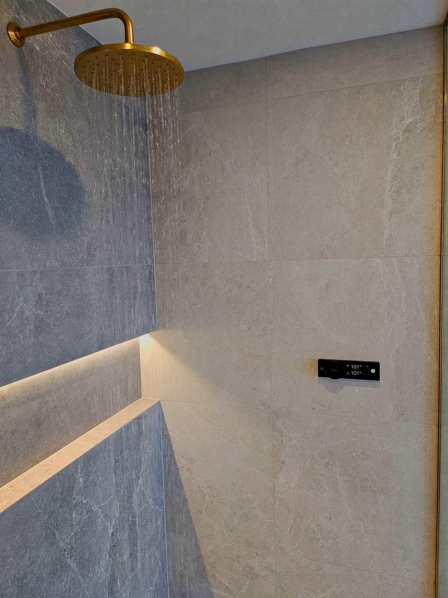 A shower head is hanging from the ceiling in a bathroom.