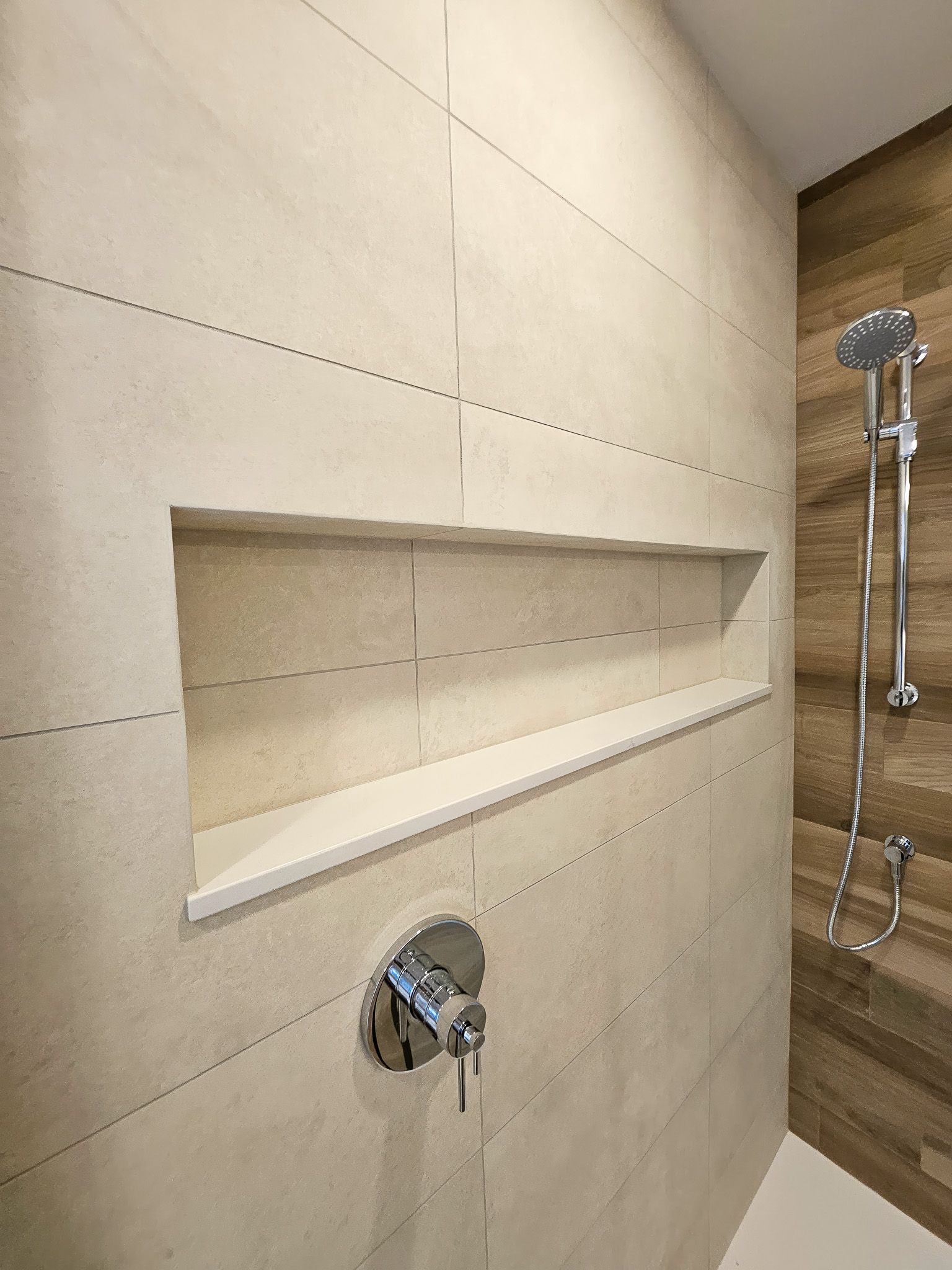 A bathroom with a shower and a shelf in the wall.