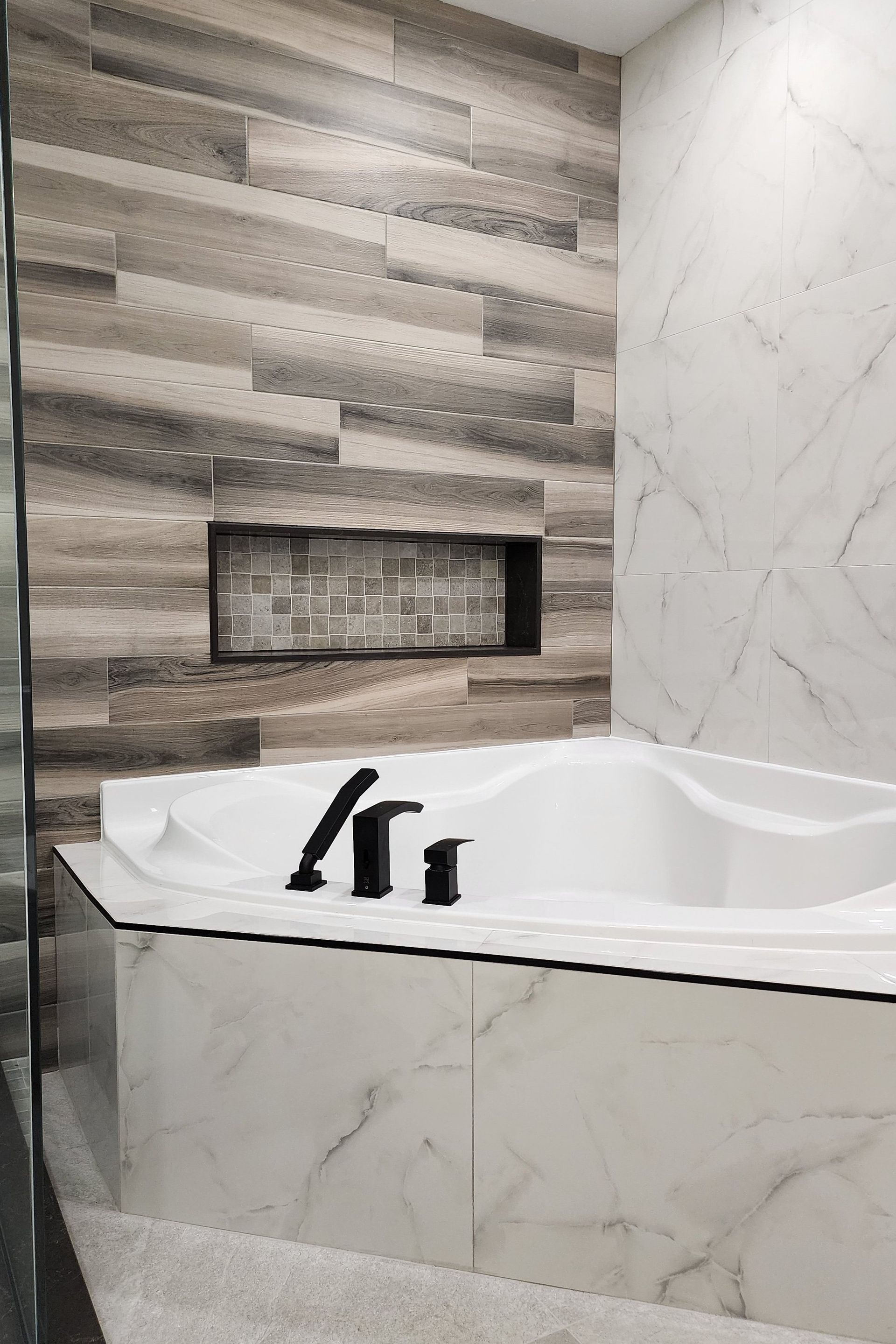 There is a bathtub in the bathroom with a wooden wall behind it.