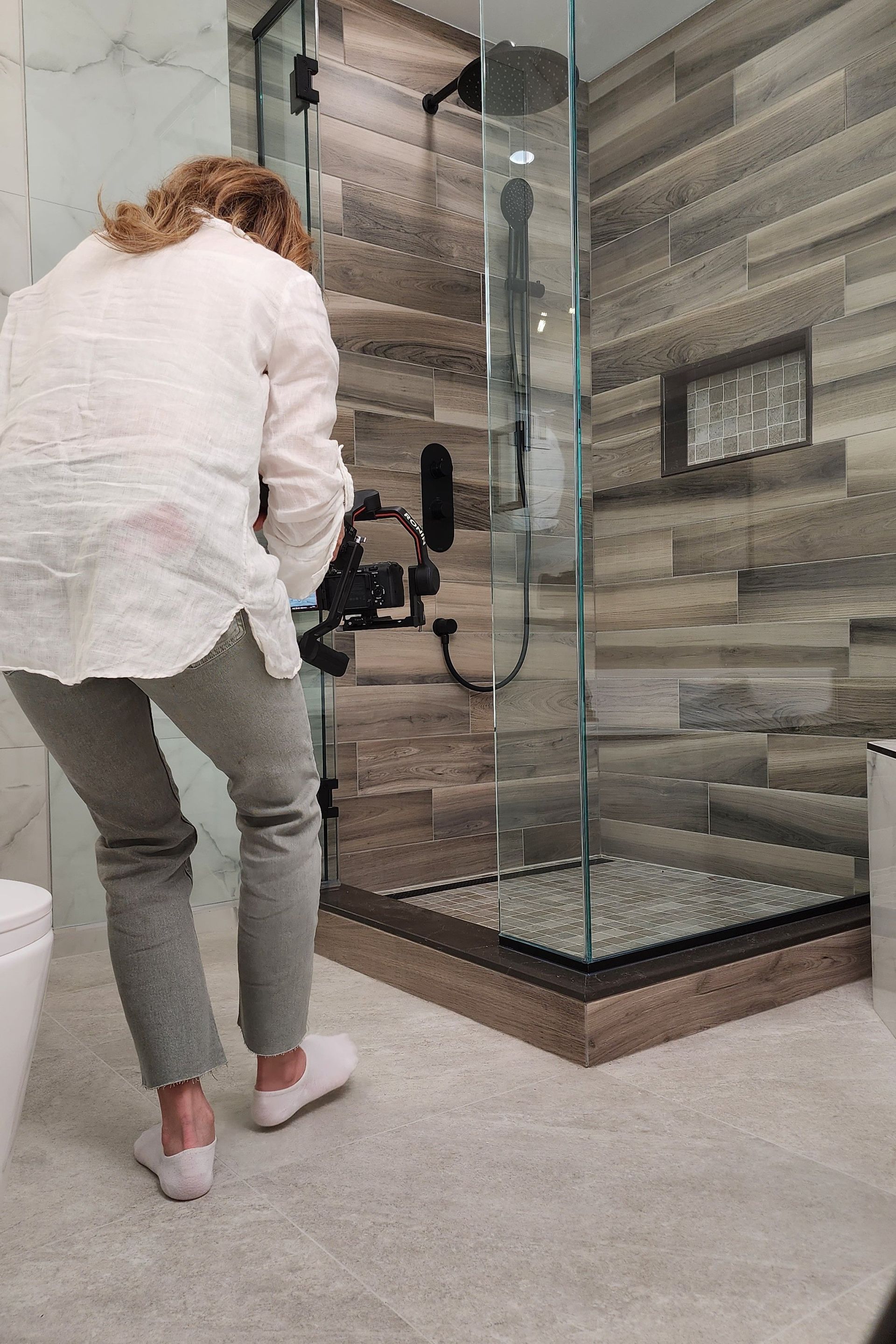A woman is taking a picture of a bathroom with a camera.