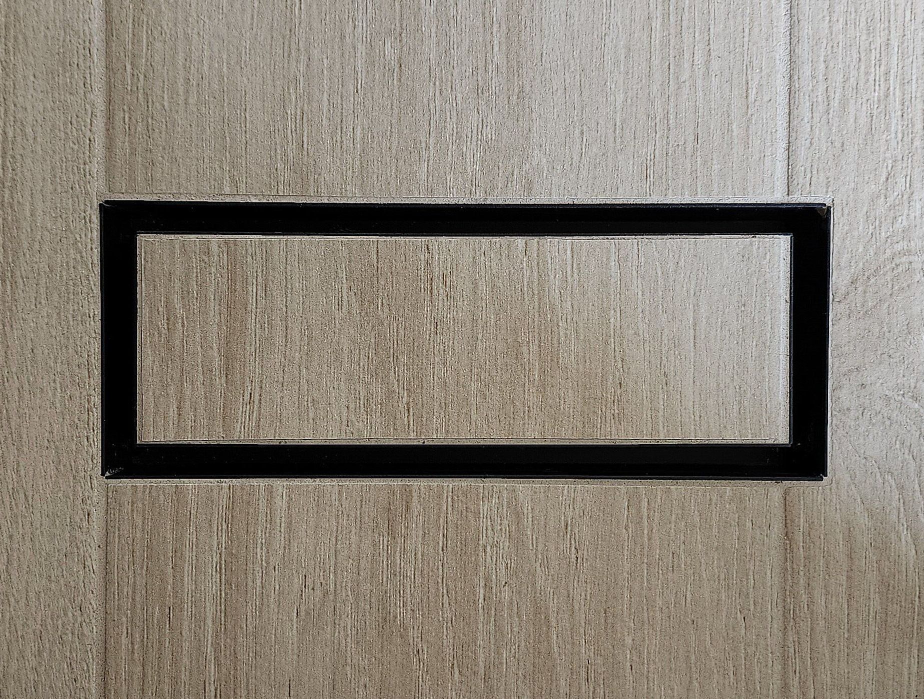 A black frame is sitting on a wooden surface.