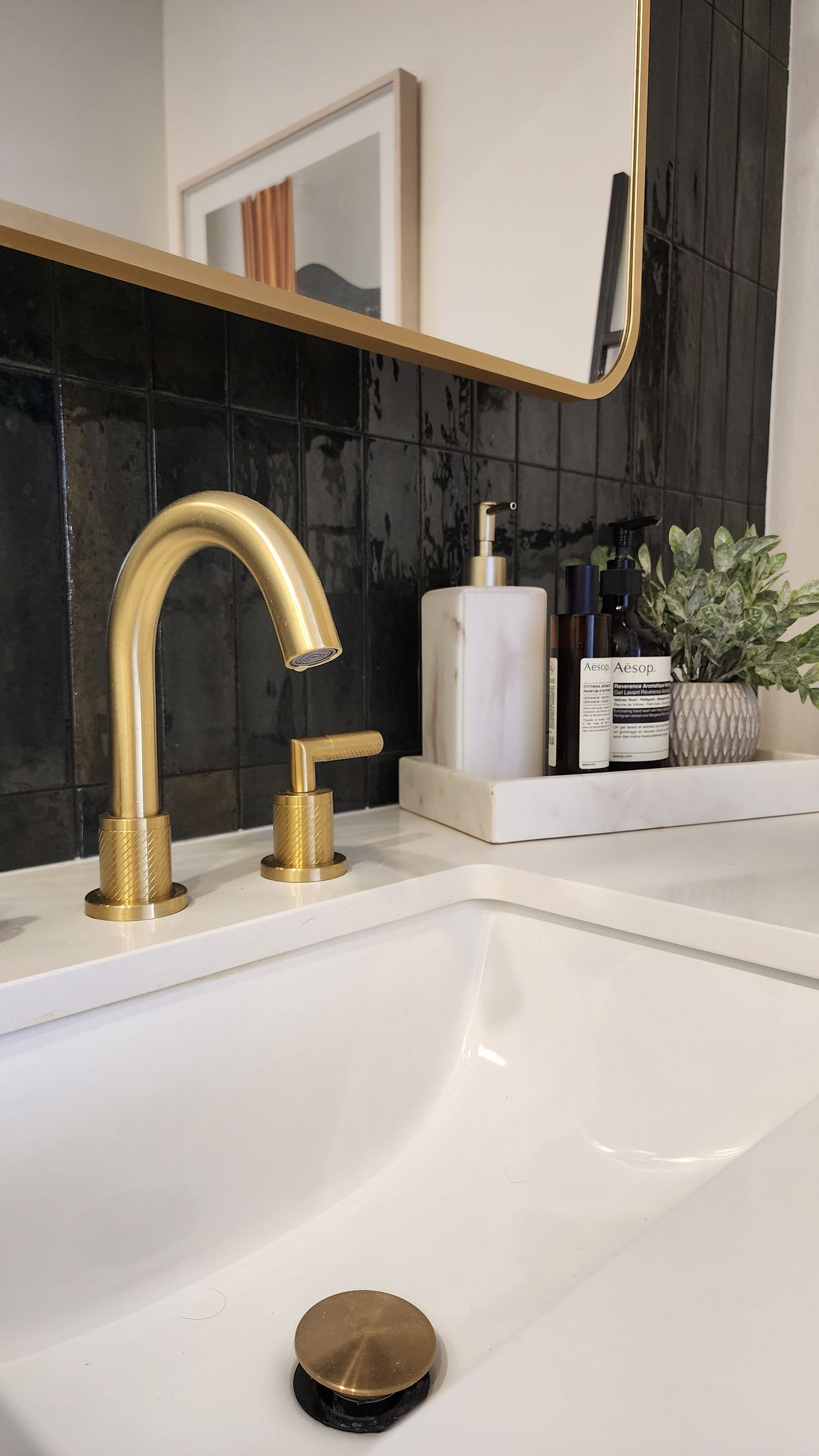 A bathroom sink with a gold faucet and a mirror.