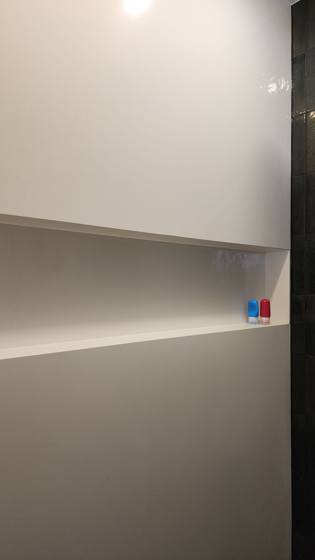 A bathroom with a white wall and a shelf in the wall.