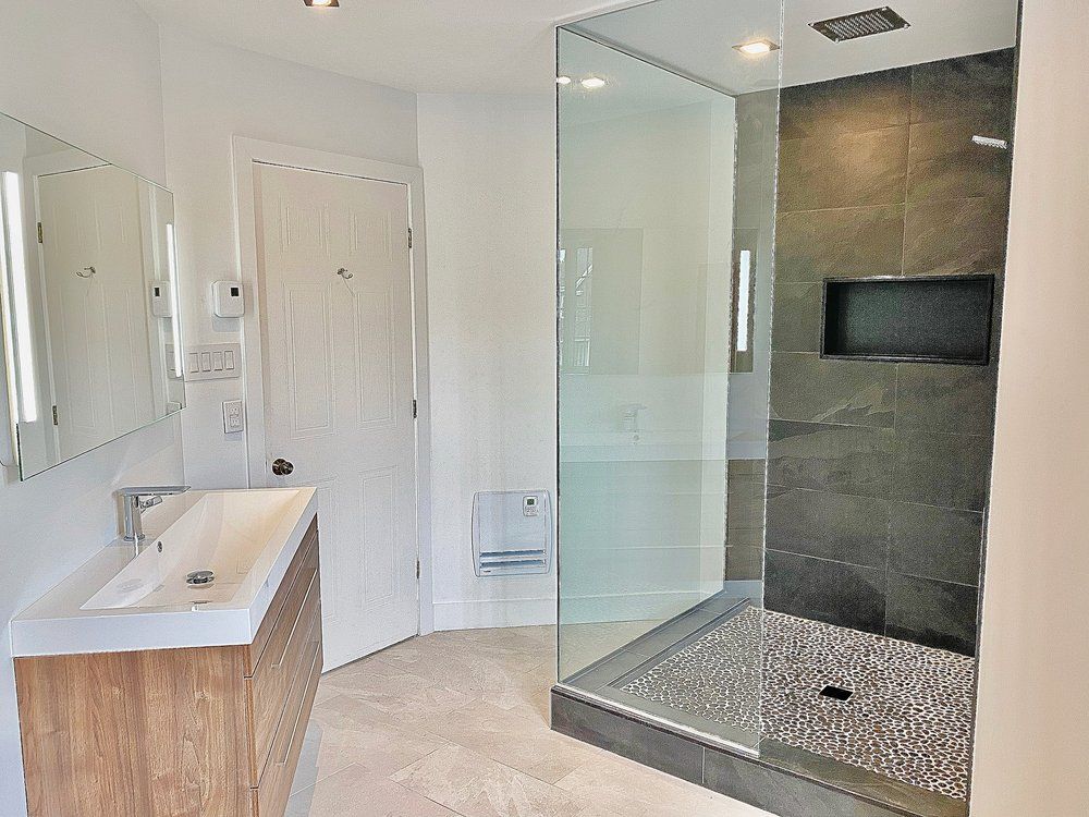 A bathroom with a walk in shower , sink and mirror.