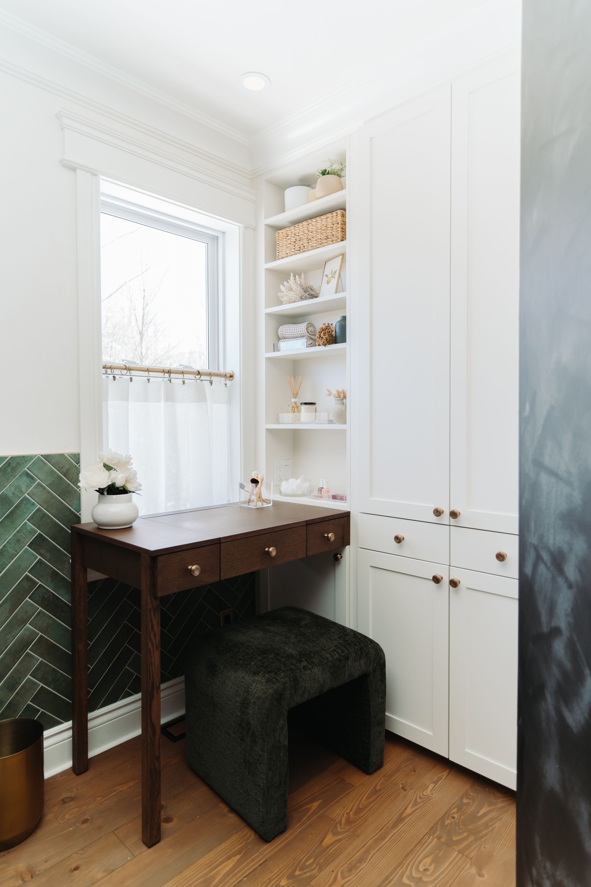 A room with a desk and a stool in front of a window.