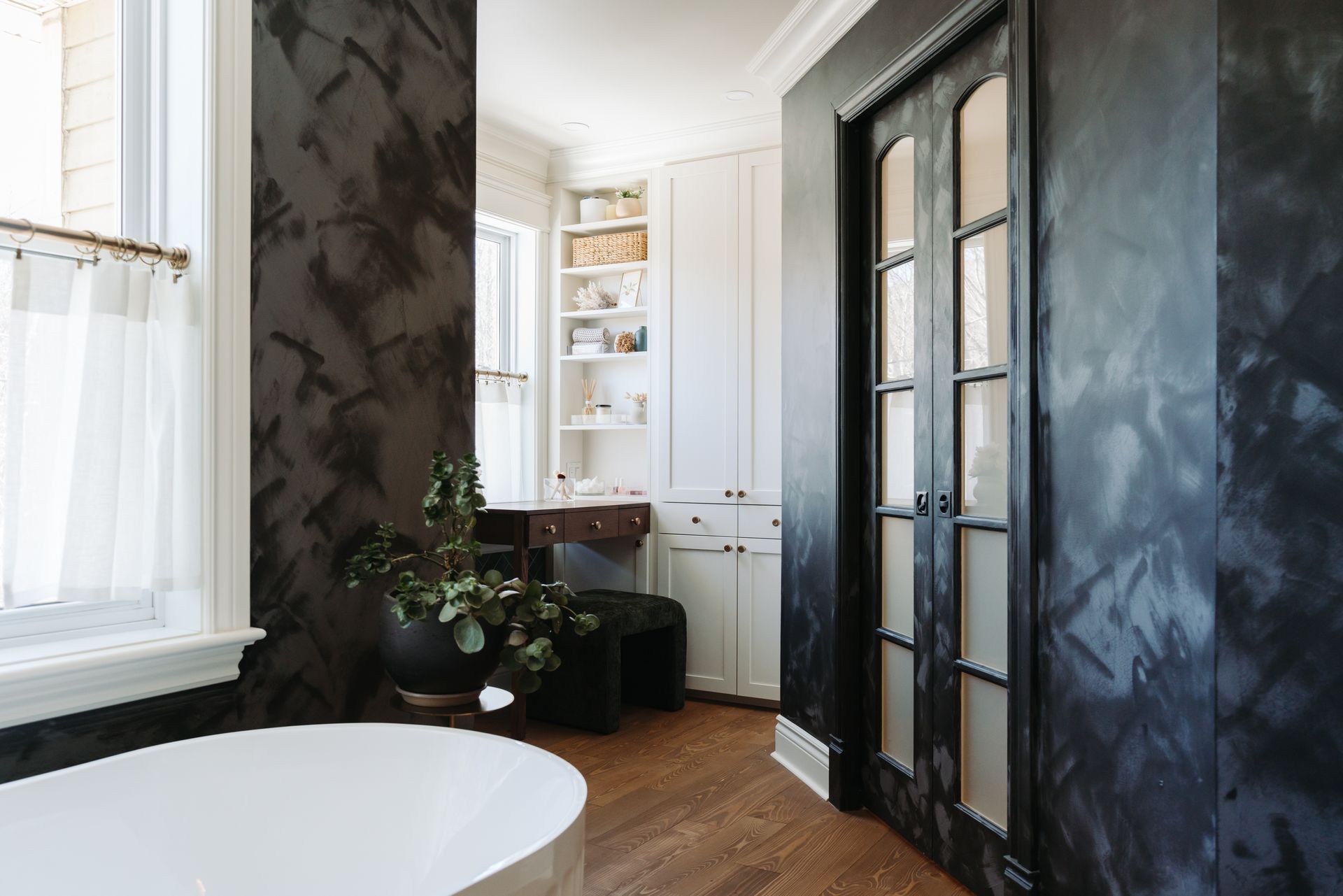 Une salle de bain avec des murs noirs et une baignoire blanche.