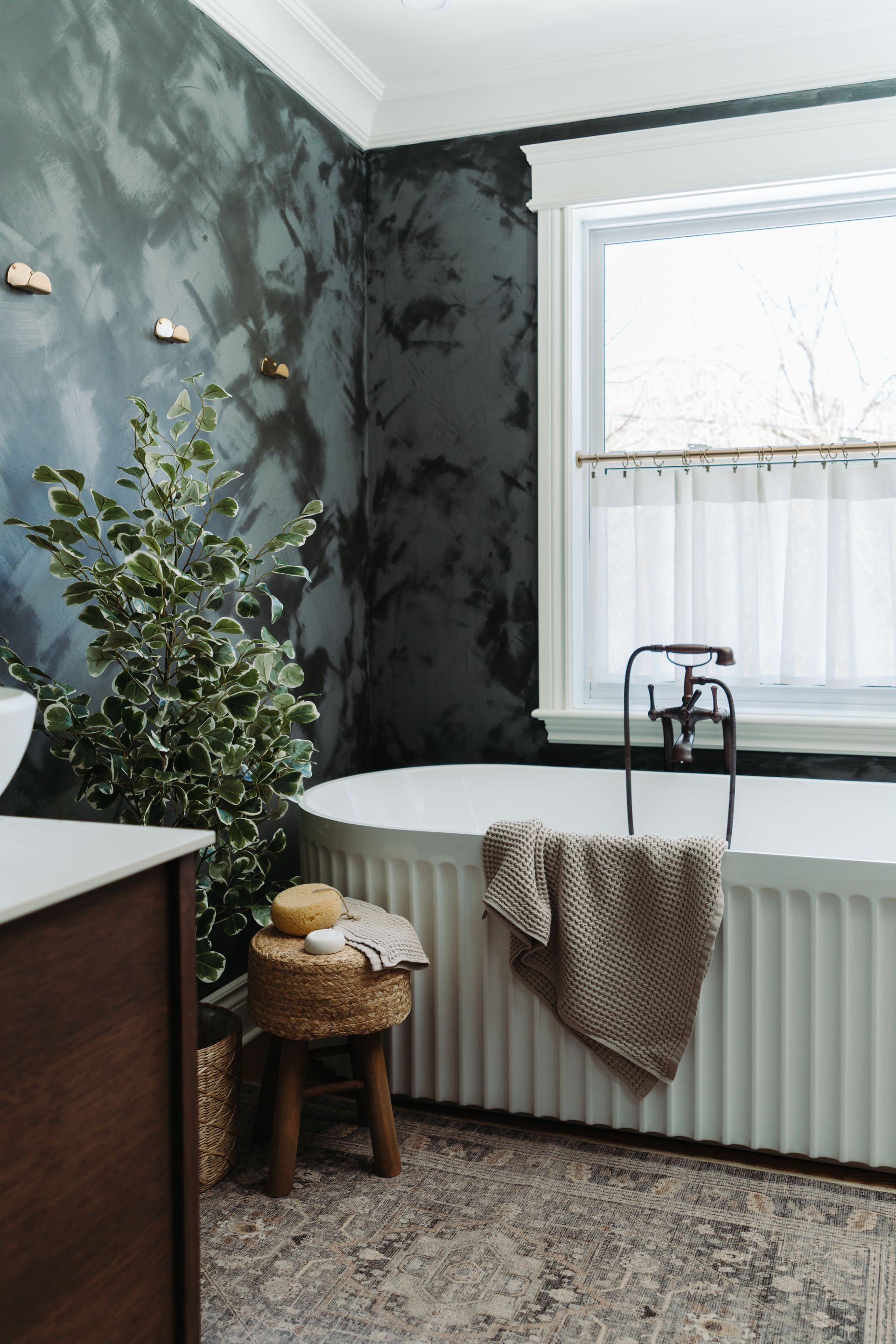 A bathroom with a tub , sink , and window.