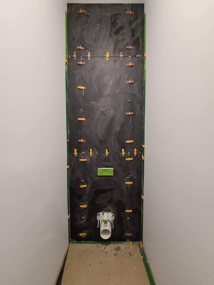 A toilet is being installed in a bathroom under construction.