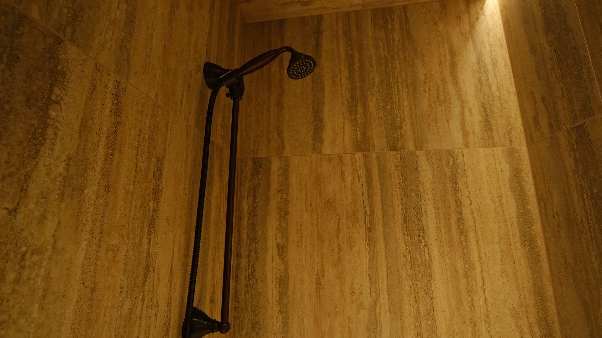 A shower head is hanging from the ceiling in a bathroom.