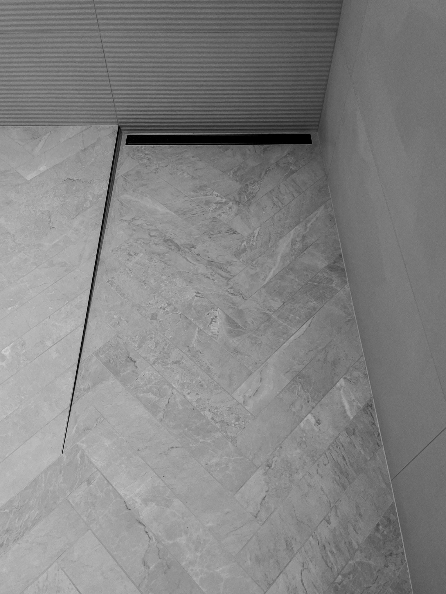 A black and white photo of a tiled floor in a bathroom.