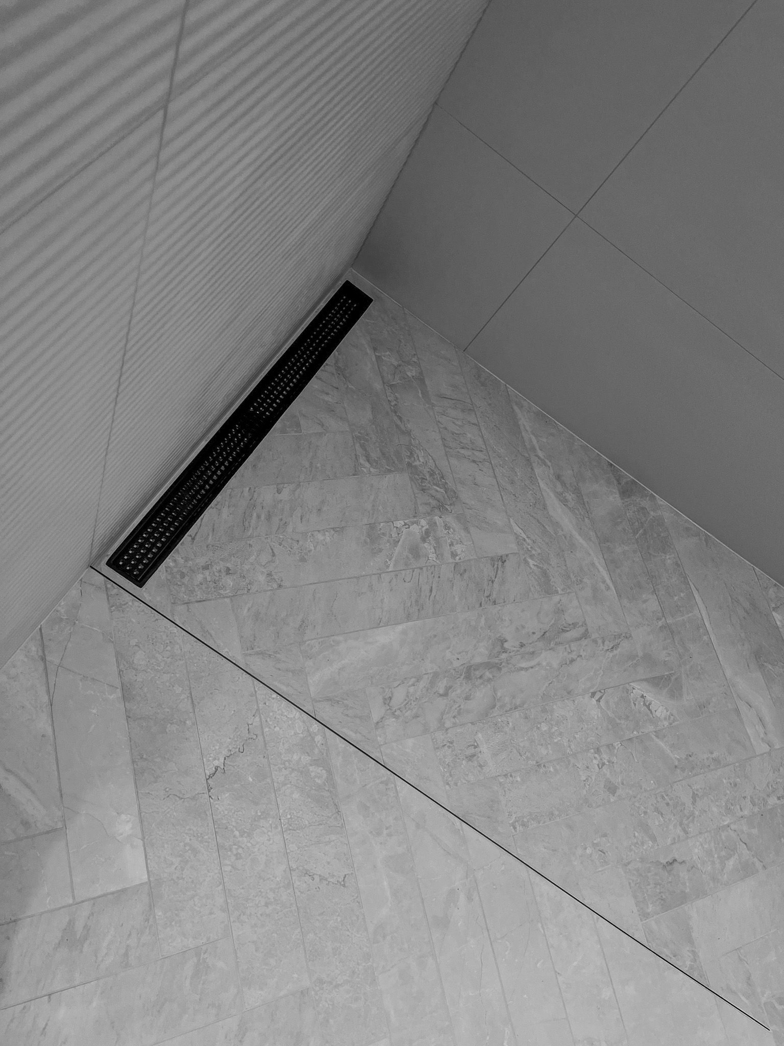 A black and white photo of a bathroom floor with a black drain.