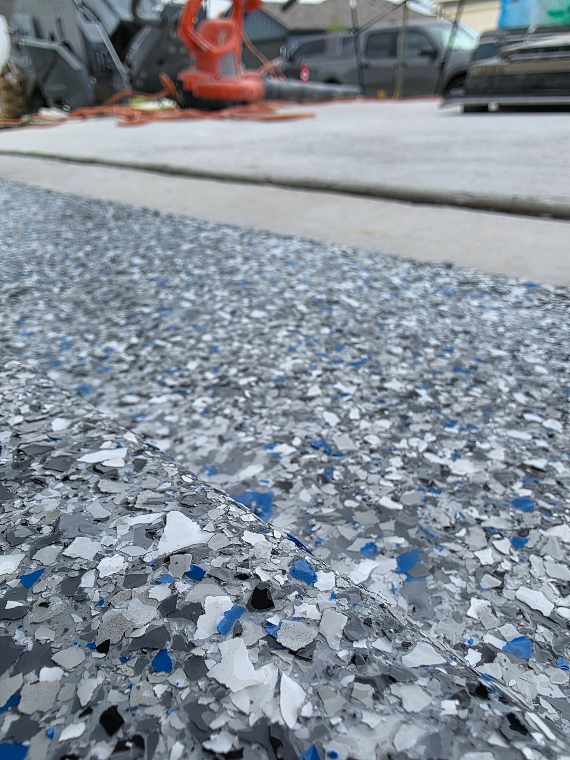 Close-up of speckled gray epoxy floor with blue flecks in an outdoor industrial area