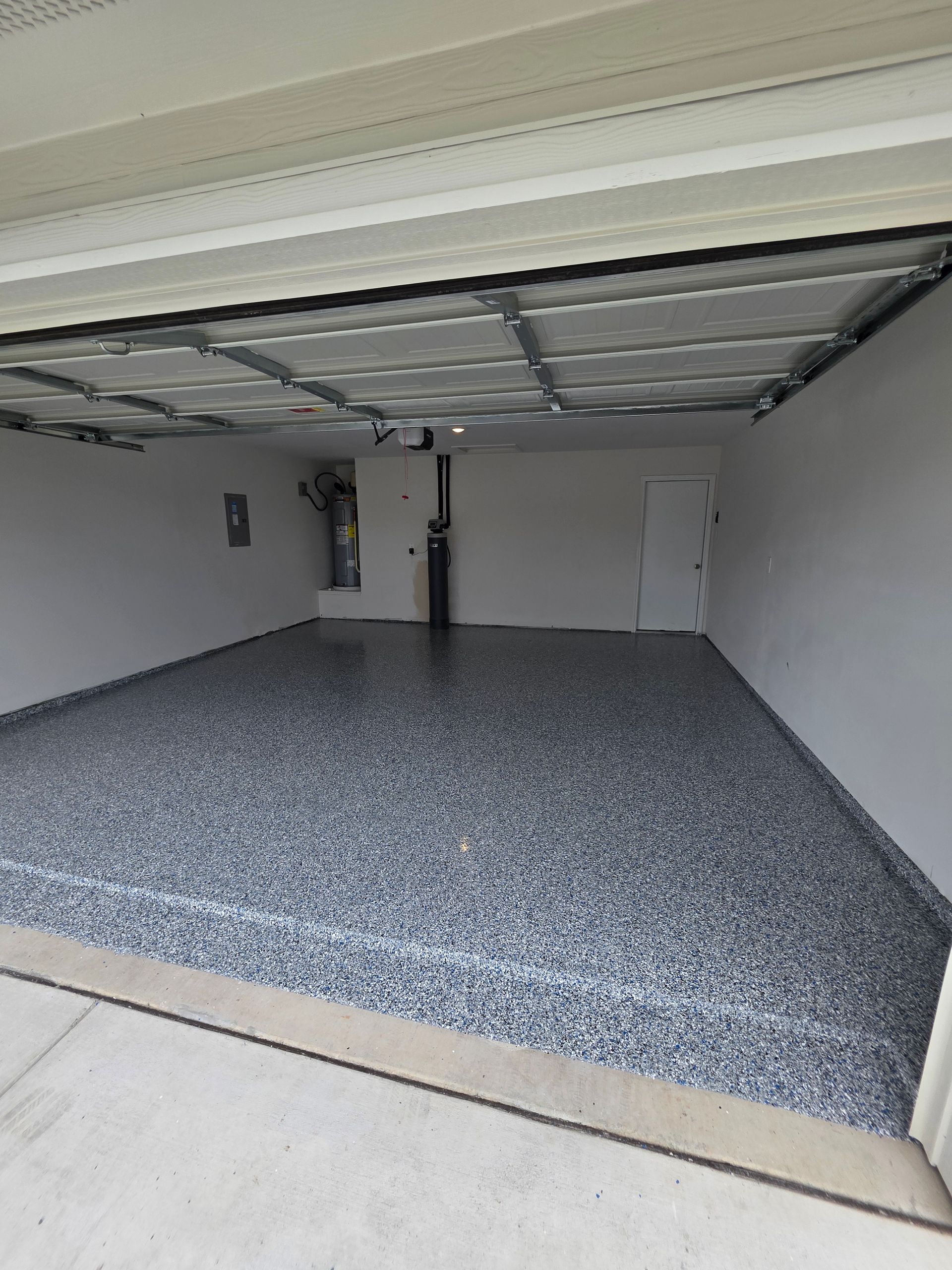 Empty garage with gray speckled floor and open overhead door。