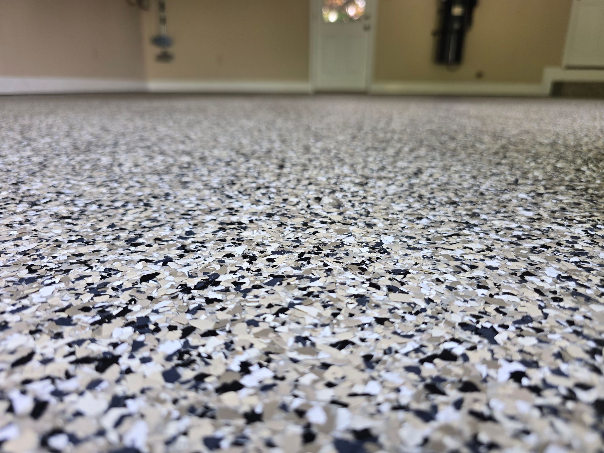 Speckled gray terrazzo floor in an indoor room with blurred walls and a doorway in the background