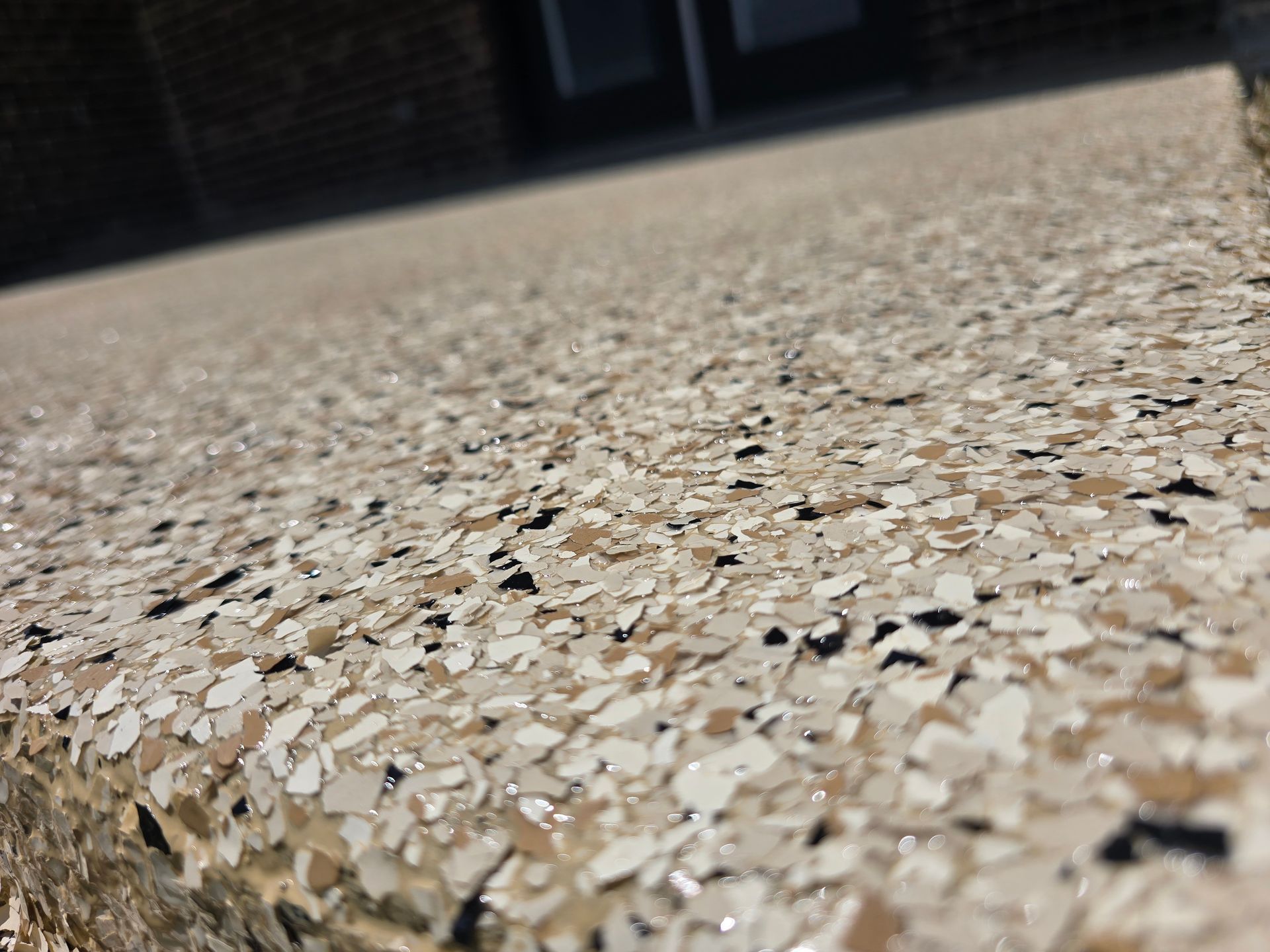 Close-up of a speckled terrazzo floor with a low-angle view toward a dark interior background