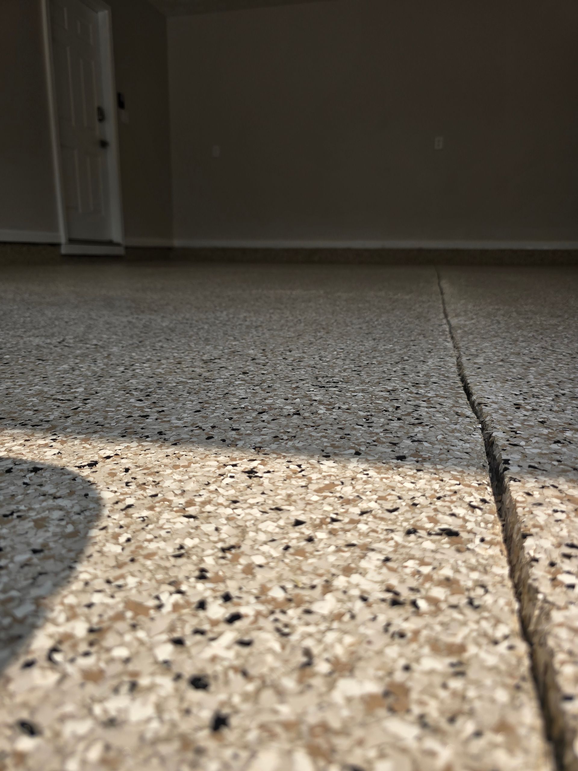 Low-angle view of speckled terrazzo floor with a crack running vertically near a doorway
