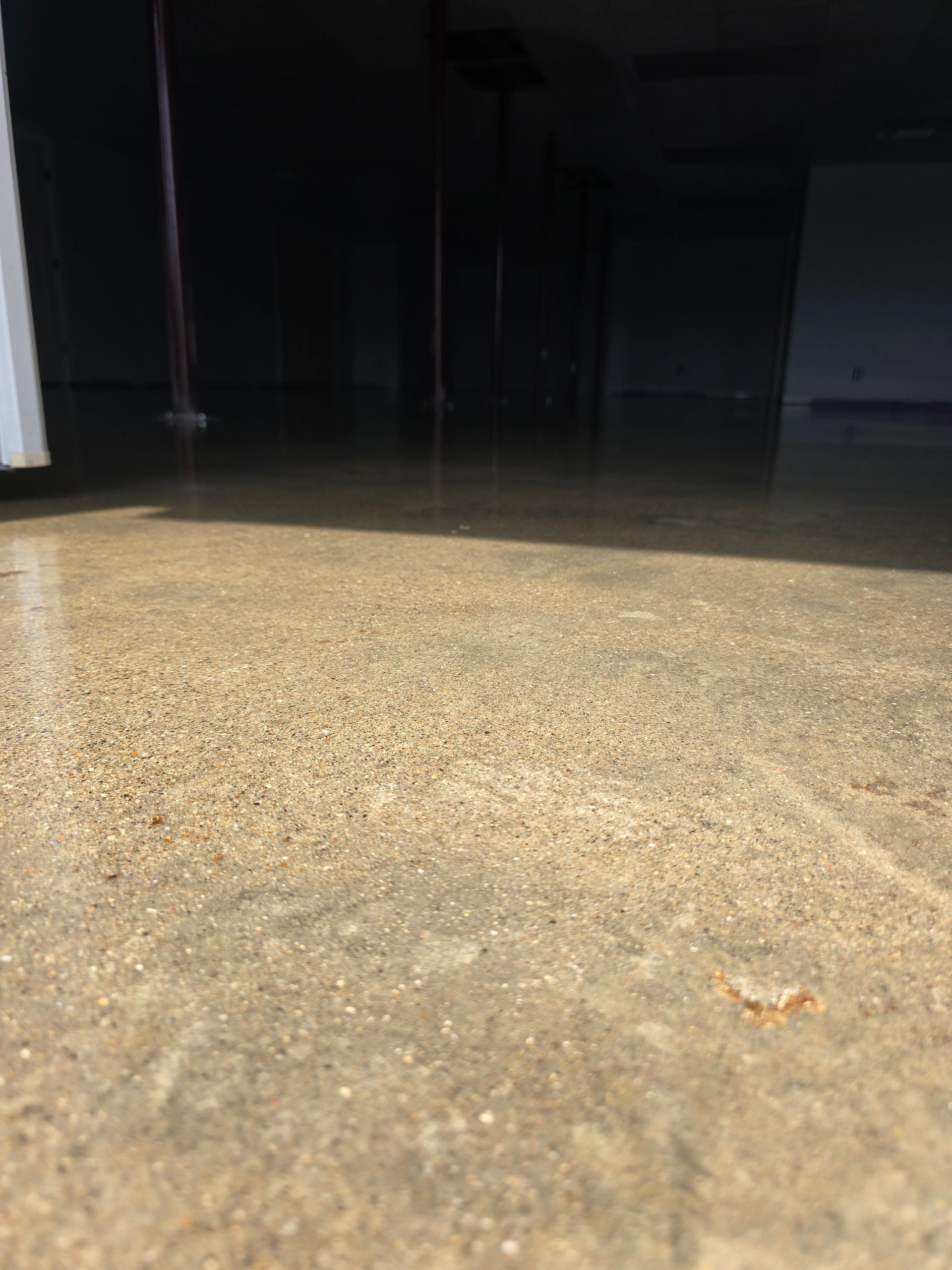 Dim indoor floor lit by a bright flash, with a dark background and a white wall edge on the left.