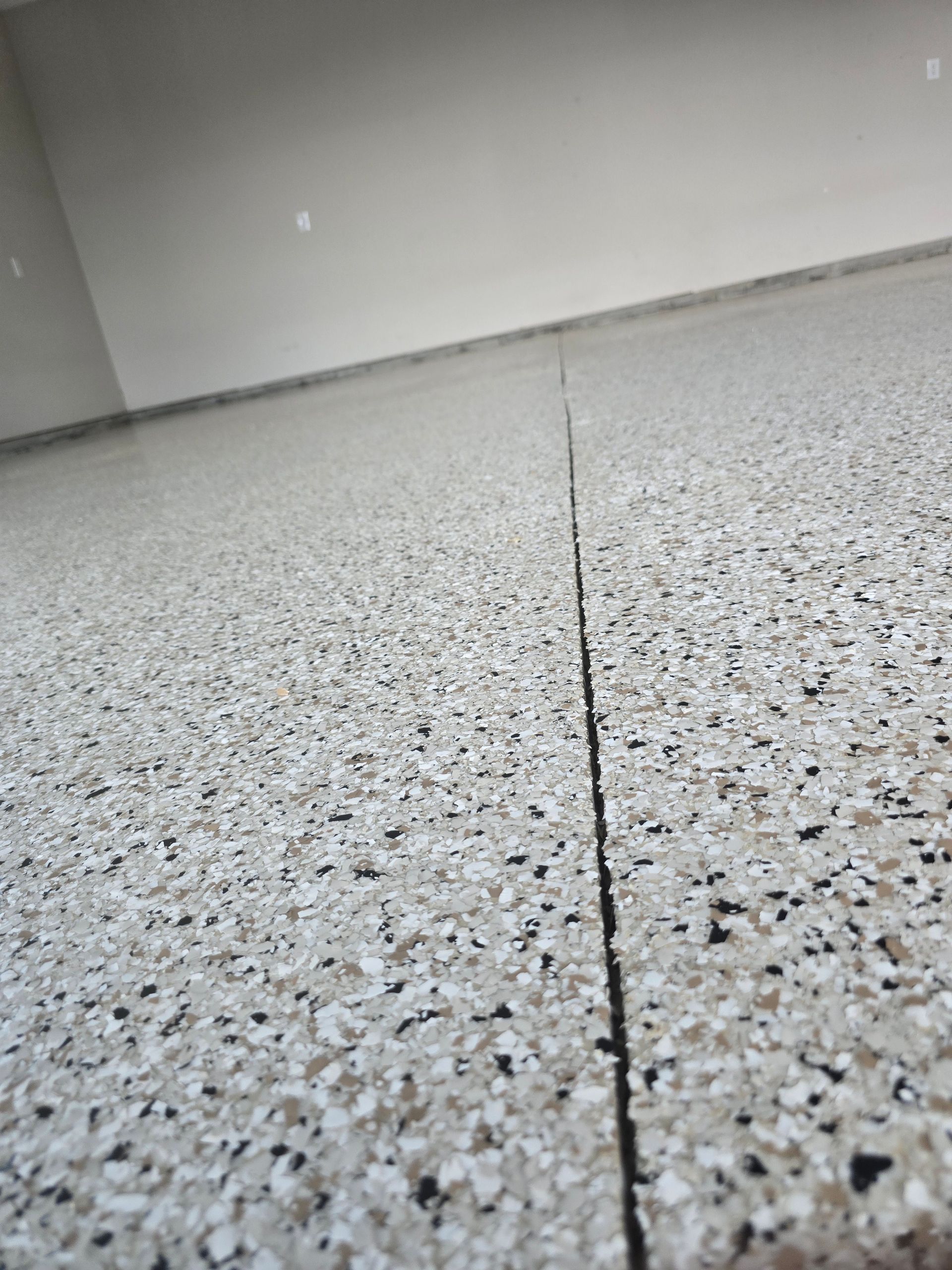 Close-up of a speckled terrazzo floor with a narrow crack running through it