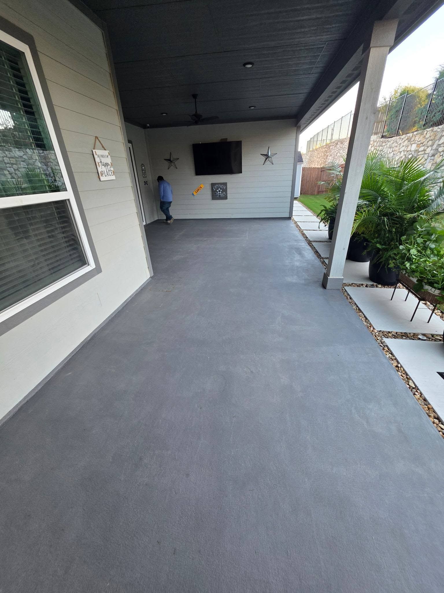 Covered walkway with gray floor, white walls, and a person standing in the distance.